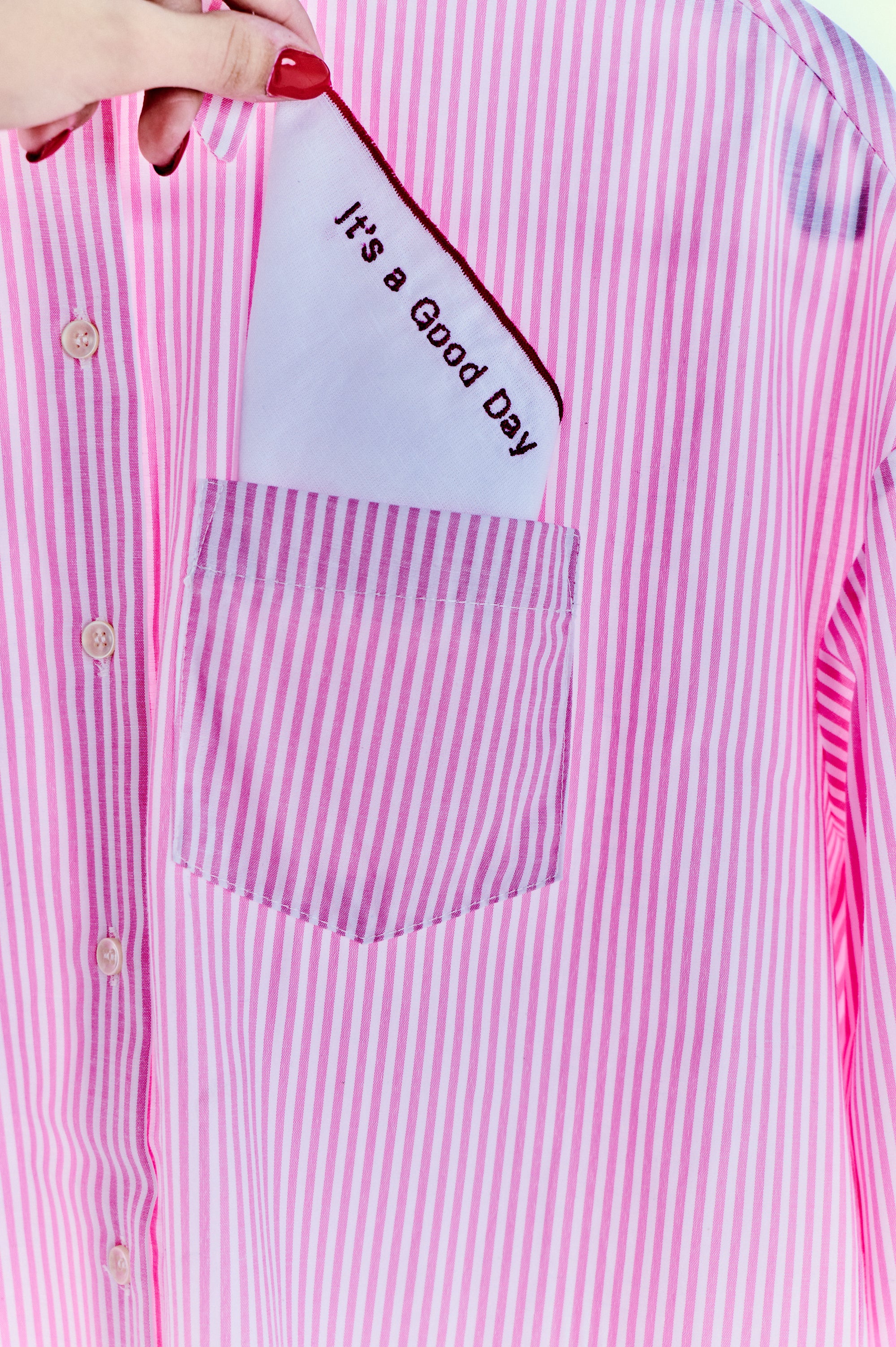 Sorbe pembe-çizgili gömlek yakın plan; “It’s a Good Day” detaylı göğüs cebi, Pentome Studio çekimi. \nSorbe pink striped shirt close-up; chest pocket with “It’s a Good Day” detail, shot at Pentome Studio.
