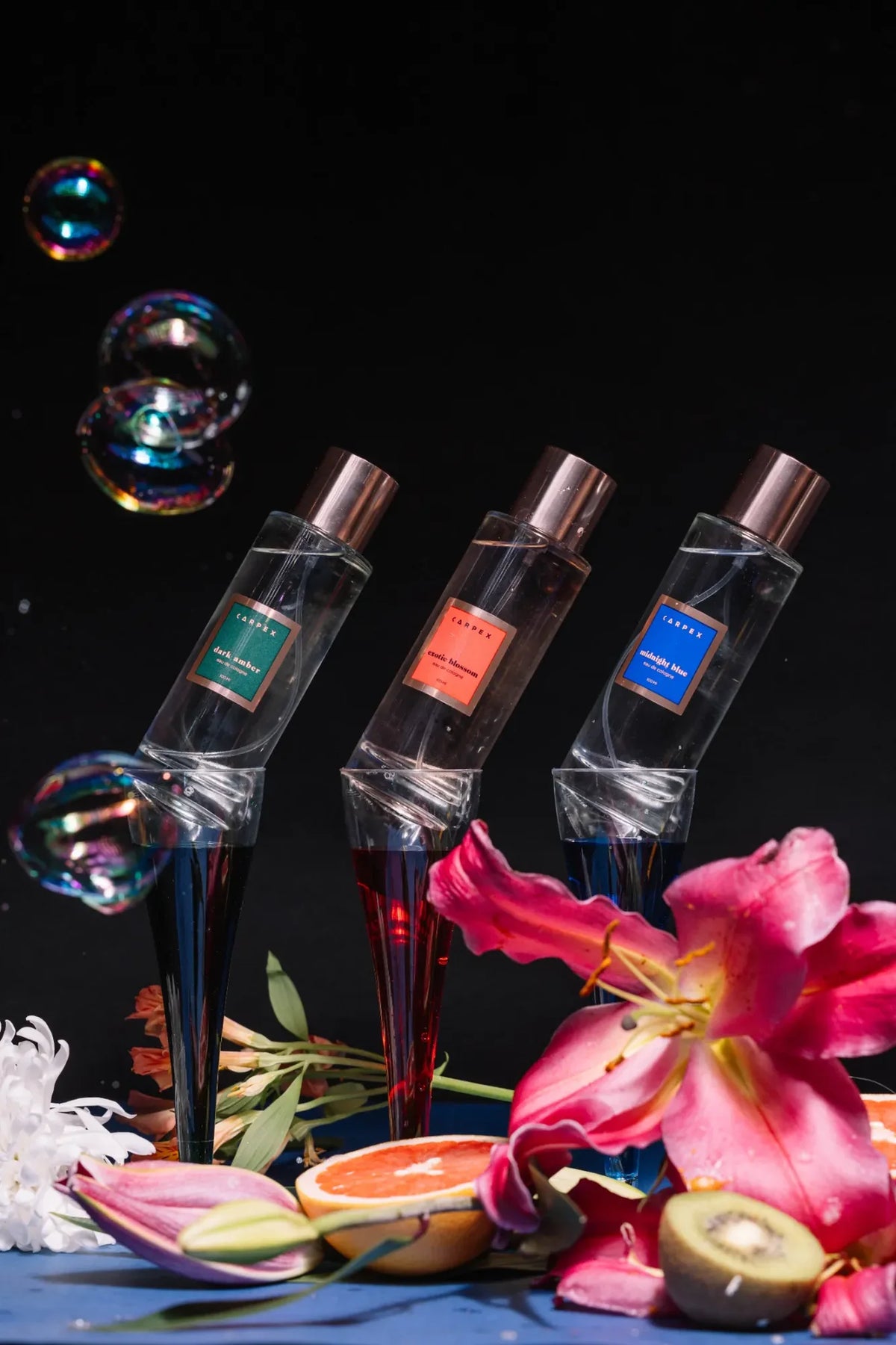 Carpex koleksiyonundaki üç farklı koku: “Dark Amber”, “Exotic Blossom” ve “Midnight Blue”, canlı çiçek ve meyve kompozisyonlarıyla sahnelenmiş. Pentome Studio’da çekilmiştir.
Three Carpex fragrances — “Dark Amber”, “Exotic Blossom”, and “Midnight Blue” — styled with vivid flowers and fruits in a creative studio setup. Photographed at Pentome Studio.
