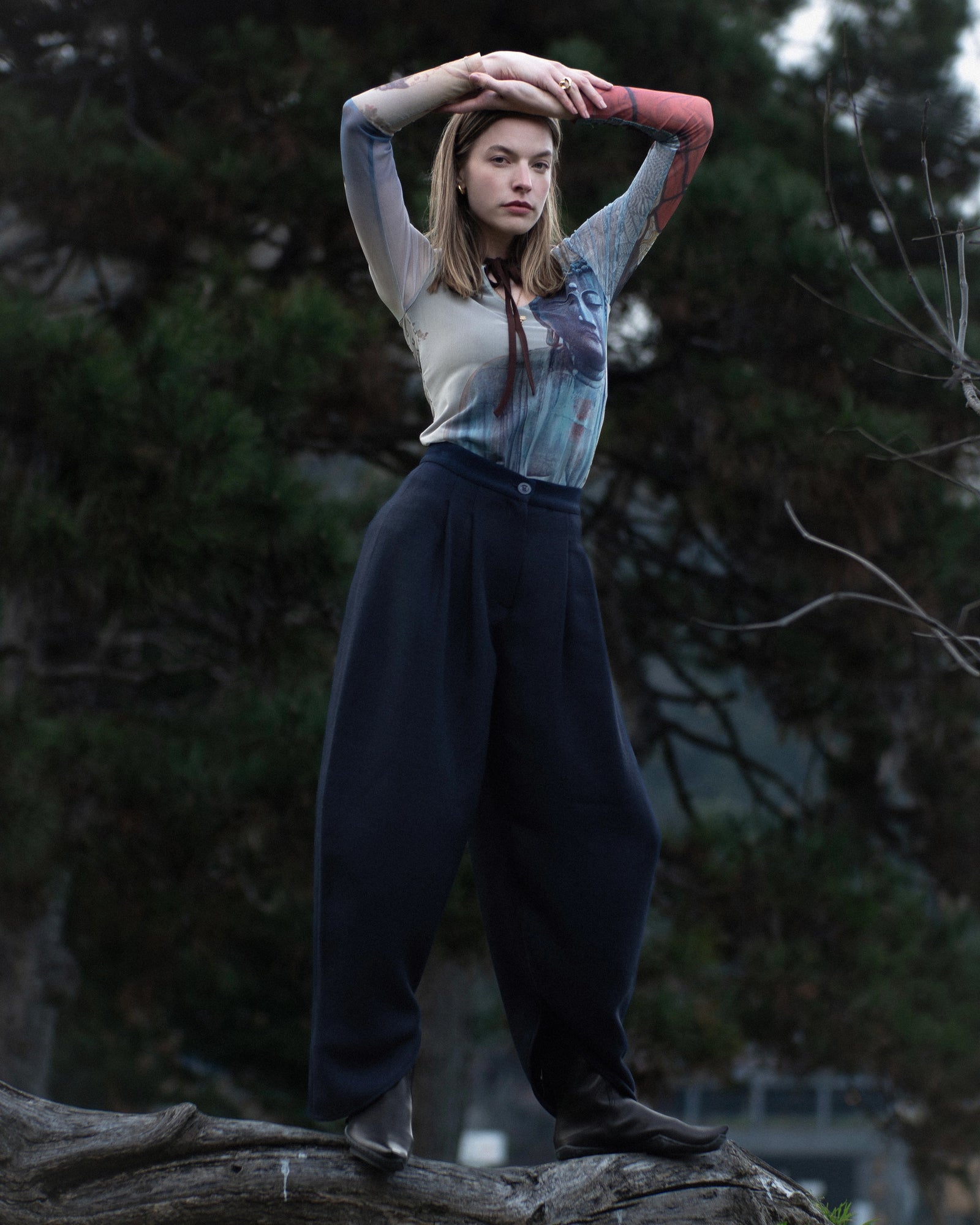 Shopigo markasına ait doğa çekimi; Buddha baskılı üst ve lacivert geniş paça pantolon kombinasyonu, zarif bir dengeyle doğal fon önünde sergilenmiştir. Pentome Studio’da çekilmiştir.
An outdoor fashion capture for the brand Shopigo, featuring a Buddha-printed top and navy wide-leg trousers styled in harmony with the forest backdrop. Photographed at Pentome Studio.