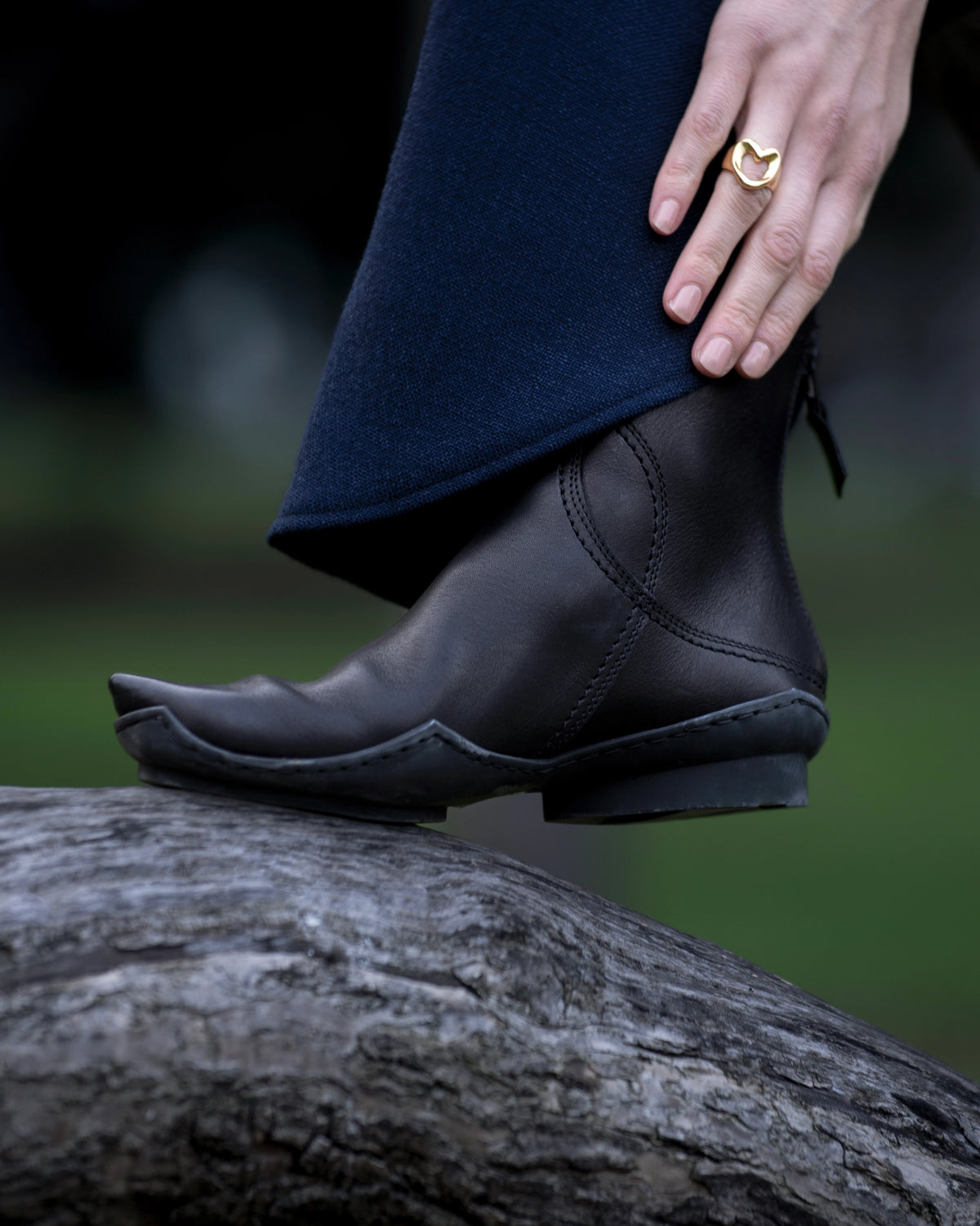 Shopigo markasına ait detay çekim; siyah deri botlar ve kalp biçimli altın yüzük, doğal zeminde sade bir zarafetle sunulmuştur. Pentome Studio’da çekilmiştir.
A close-up detail shot for the brand Shopigo, featuring black leather boots and a heart-shaped gold ring, captured with natural elegance on a rustic surface. Photographed at Pentome Studio.