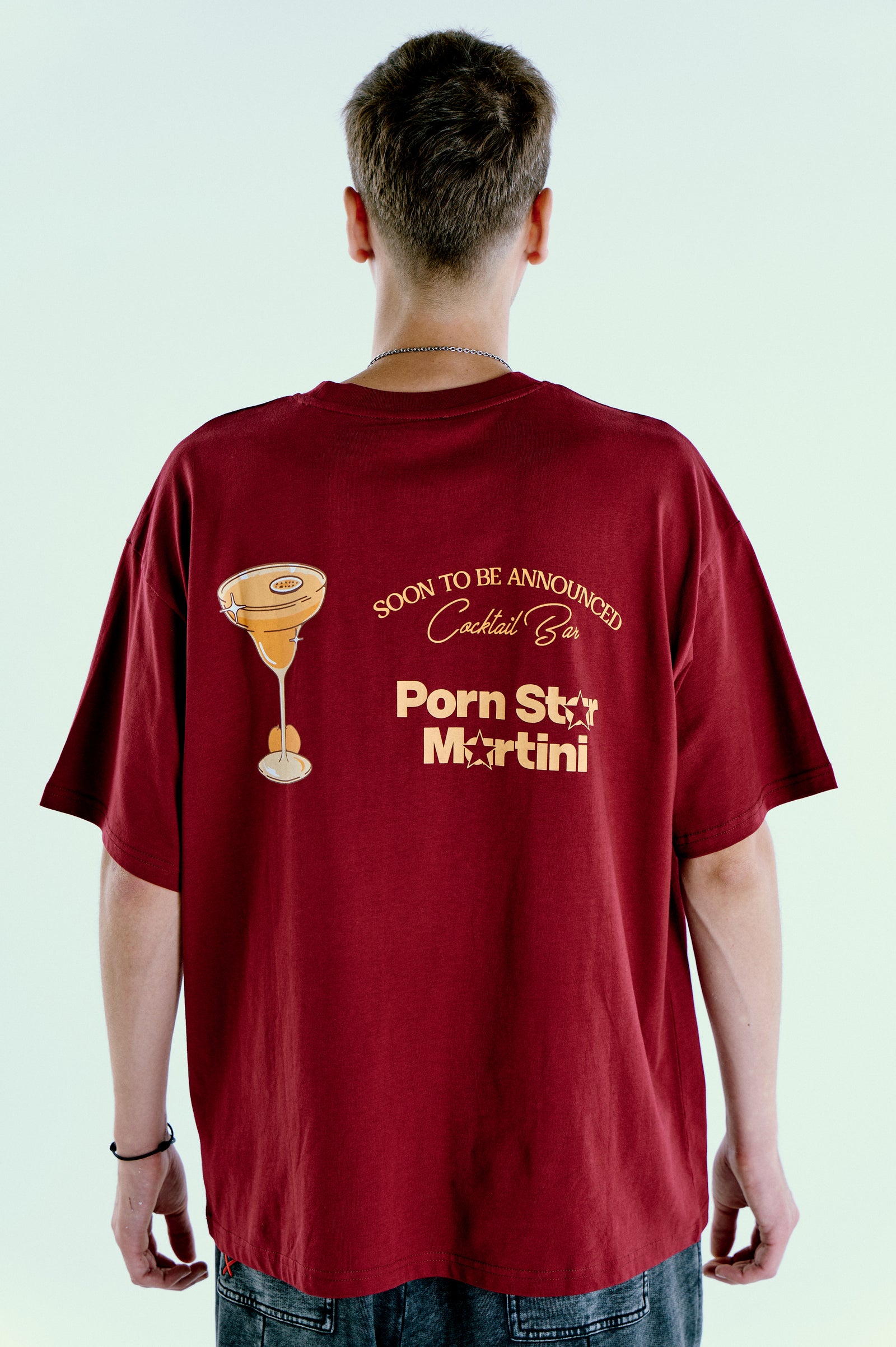 Soontobeannounced bordo tişört arka baskı; model üzerinde “Porn Star Martini” grafik, Pentome Studio. \nSoontobeannounced burgundy tee back print on model; “Porn Star Martini” graphic, Pentome Studio.
