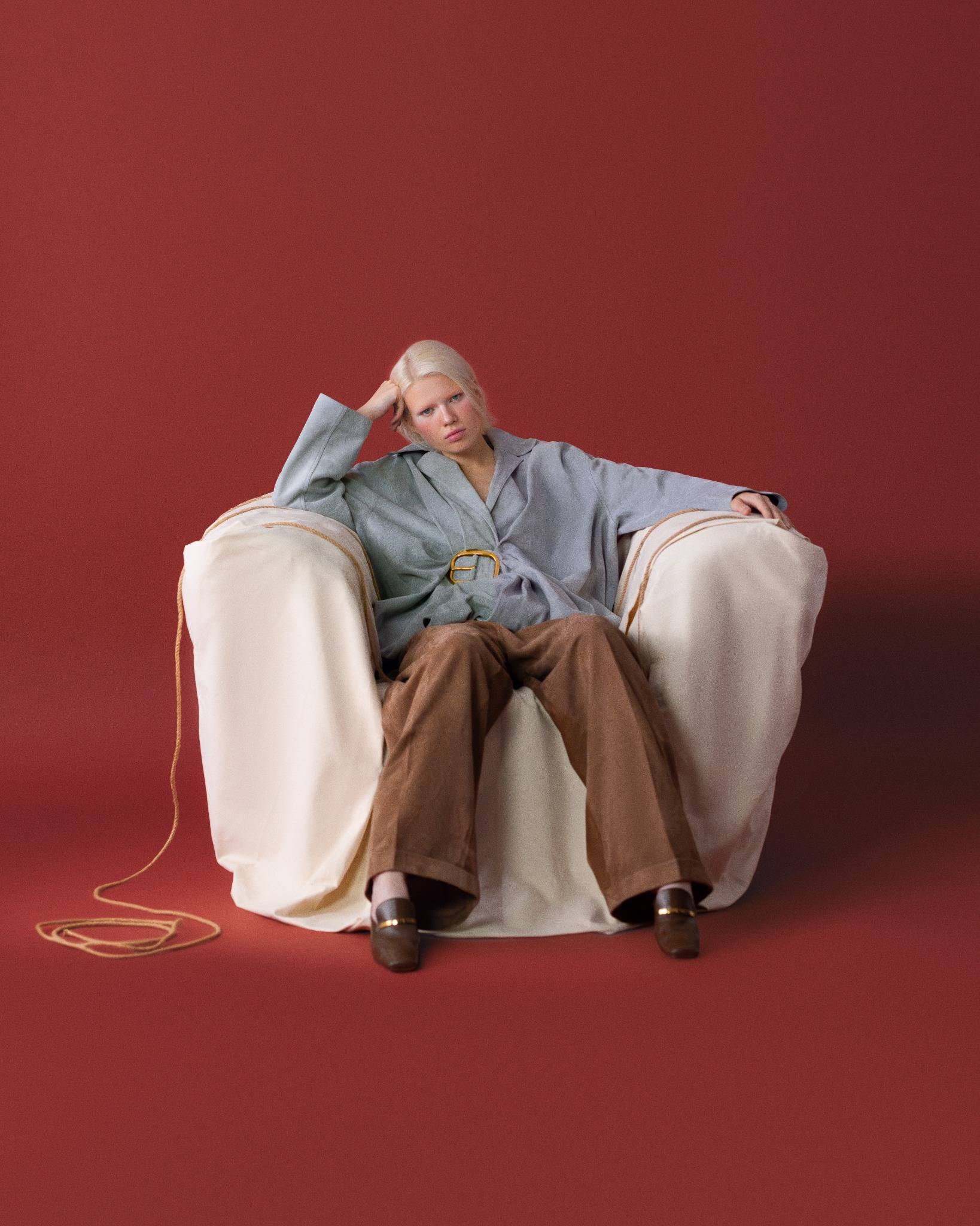 Vogue Türkiye September 2024 editoriyali; kiremit kırmızı fonda, beyaz örtüyle kaplı büyük koltukta dinlenen model — gri kuşaklı ceket ve kahverengi bol paça pantolonla sakin sahne.

Vogue Turkey September 2024 editorial; model lounging on an oversized armchair draped in white fabric—grey belted jacket and wide-leg brown trousers against a terracotta-red backdrop.slider_item_mHAgzm